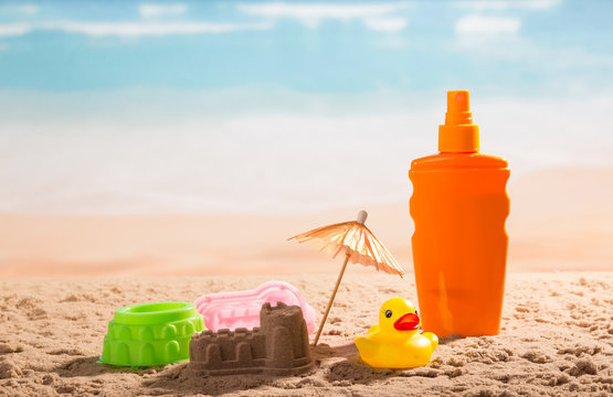Sunscreen, sandcastle, umbrella and children's toys onseashore.