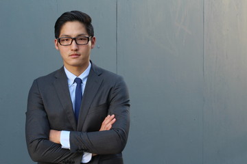 Young fashion Asian man wearing suit, tie and glasses with space for copy 