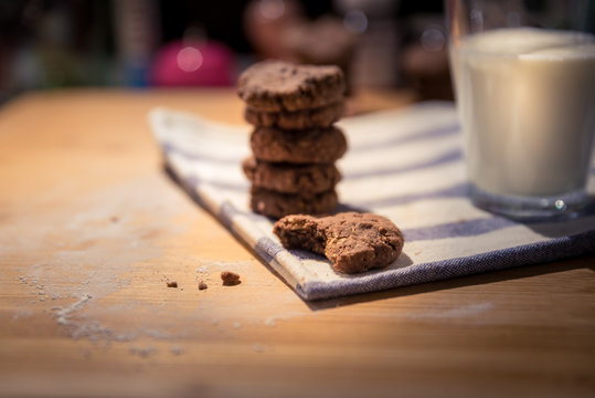 fresh cocoa cookies lie on the cloth on the wooden desk with glass of milk