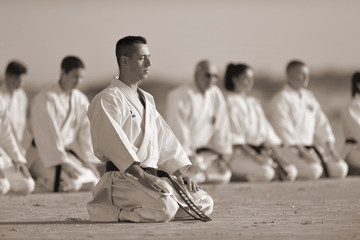 People in kimono sitting on the sand with their sensei on front - obrazy, fototapety, plakaty