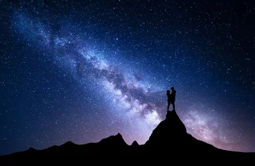 Rolgordijnen Milky Way with silhouette of people. Night landscape with starry sky. Standing man and woman on the top of mountain. Hugging couple against milky way. Beautiful galaxy. Universe. Travel. Bright stars © den-belitsky
