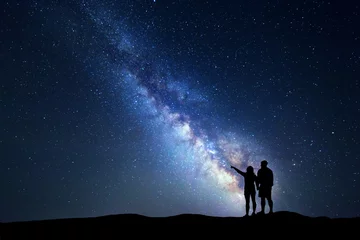 Keuken foto achterwand Nacht Melkweg met mensen op de berg. Landschap met nachtelijke hemel met sterren en silhouet van staande gelukkige man en vrouw die met de vinger in de sterrenhemel wijzen. Blauwe Melkweg. Heelal. Heldere sterren
