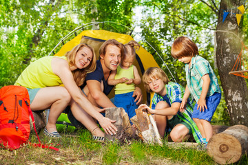 Fototapeta premium Happy young family making camp fire in the woods