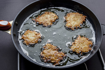 Frying latkes with ready side up in deep oil on the pan from side
