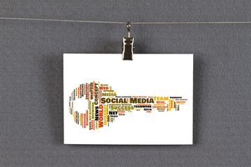 Social Media word cloud shaped as a key on a business card pinned up on a board