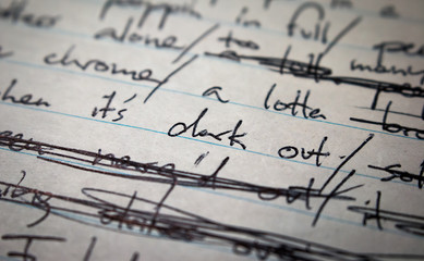 Lyrics written on paper in black ink close up. Focus on the words "it's dark out"