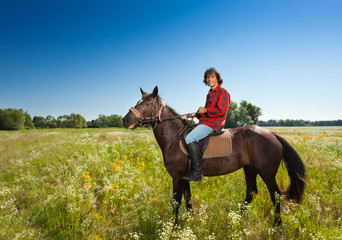 Happy male equestrian on bay horse at the meadow