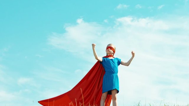 Powerful super hero girl child 7-8 years old protects the world against the blue sky. Zooming