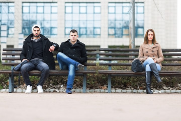 Group of friends sitting on a bench in park separately