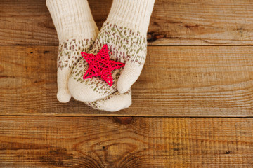 Woman hands in light teal knitted mittens are holding star 