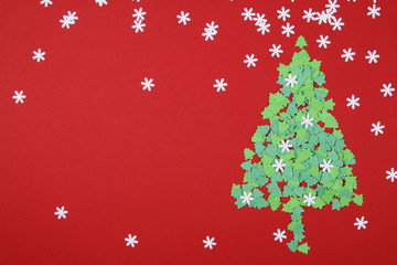 Fototapeta na wymiar Paper cut christmas tree with snow flakes on red background