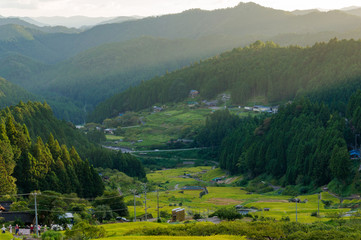 Sunset view with sun rays over countryside mountains, rice field