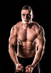Fototapeta na wymiar Young bodybuilder man stretching muscles on a black background
