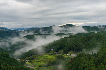 Aerial of Japanese village in mountains in foggy morning
