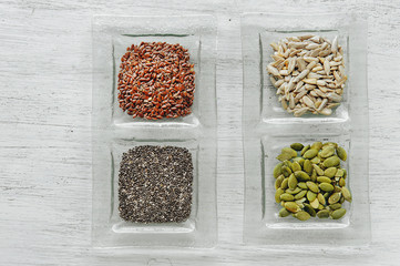 Different seeds in glass plate on the white wooden table