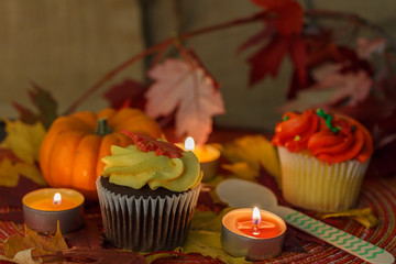 Pumpkin cupcakes with pumpkin, maple leaves, and candles. 