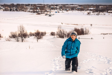 boy climbs a snow-covered banks of the river
