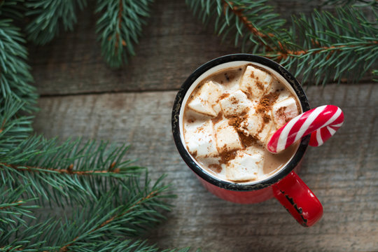 Christmas drink. Hot chocolate with marshmallows and candy cane on the wooden background. Hot cocoa with marshmallows. New Year. Holiday card. Rustic style. Close up.