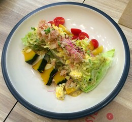 A full dish of healthy salad - lettuce pumpkin and tomato - on top with white crab and egg