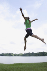 Teen girl jumping by lake