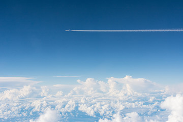 Airplane flying above white cloud in blue sky