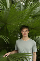 young man standing in tropical plants