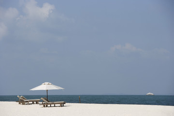 two lounge chairs on white sand beach