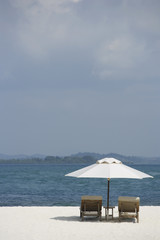 Fototapeta na wymiar two lounge chairs on white sand beach