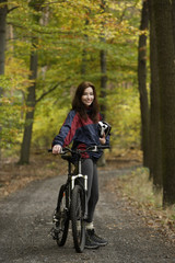 Fototapeta na wymiar Young woman taking rest from biking through forest