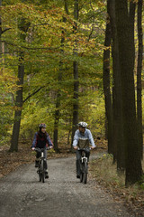 Young couple riding bikes through forest