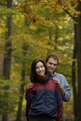 Young couple in hiking clothes standing in forest