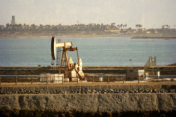 aged and worn vintage photo of oil derrick with body of water