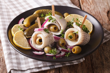 Tasty rollmops stuffed olives, onions, pickles and lemon close-up on a plate. horizontal