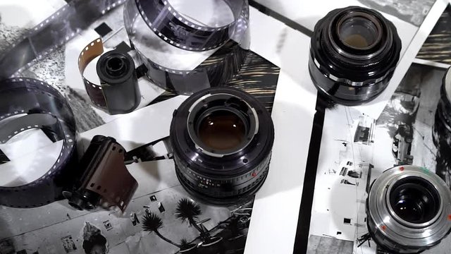 Vintage 35mm cameras, lenses, photos and film are piled up.