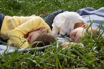 brother and sister lying on blanket in park