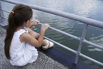 young girl sitting over lake