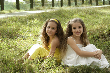 two young girls sitting in field