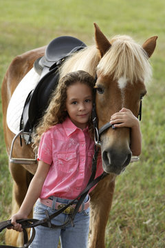 Young girl hugging nose of pony