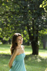 young woman outside smiling trees in background