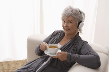 Older woman listening to music while drinking tea.