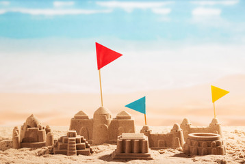Sand castles, towers and flags Coliseum on background of sea.