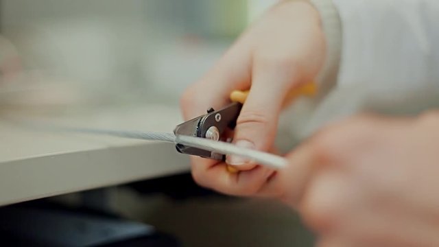 Work with fiber optic cable / Male hands cut off unnecessary insulation from cable and remove screen braid during preparing to installation.