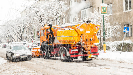 city street covered with snow during heavy winter storm in one European capital city, vehicles defocused due to its movement, snowplough shoveling roads