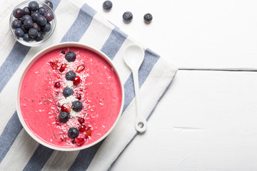 Strawberry and beetroot smoothie bowls topped with blueberries, pomegranate, chia seeds and shredded coconut. Top view and copy space