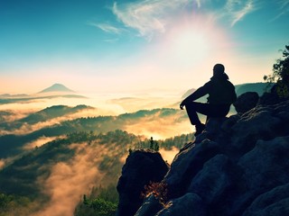 Hiker man take a rest on mountain peak. Man lay on summit, bellow autumn valley.