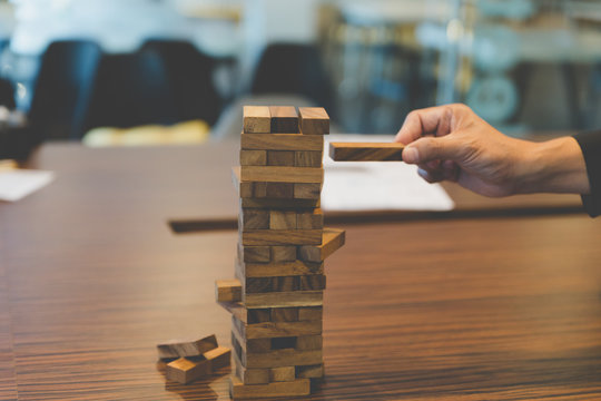 businessman gambling placing wooden block on a tower - planning,