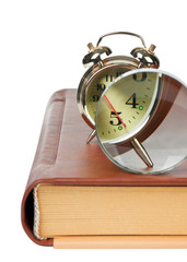 golden alarm clock and magnifying  glass on the book isolated