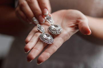 Wedding earrings on a bridal hand, bride's morning and jewelry accessories and decoration concept