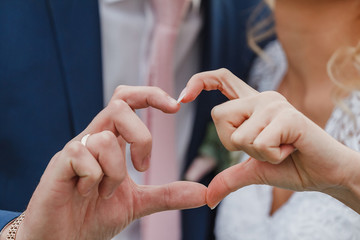 the bride and groom's hands make a heart shape