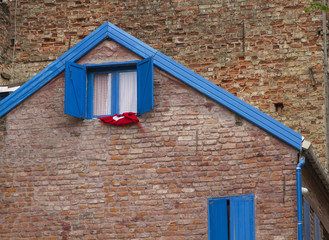 Brown old brick house with blue wooden window shutters